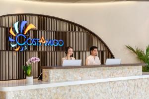 two people sitting at a reception desk with laptops at Costamigo Phan Thiet, BW Premier Collection in Phan Thiet +58 photos