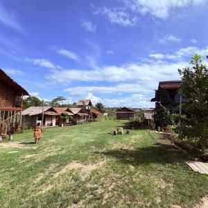a woman standing in a field next to a village at Rumsram Homestay by Rumah Etnik Papua Sorong in Papermaranda