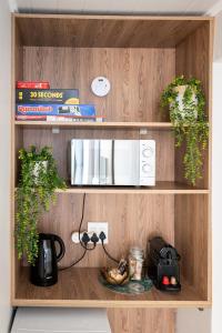 a wooden cabinet with a microwave and plants on it at OceanBreeze50 Stylish Garden Route Stay in Central Mossel Bay in Mossel Bay
