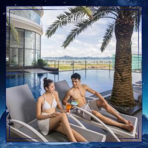 a man and a woman sitting on a lounge chair by a pool at Terra Bay Homestay in Ha Long