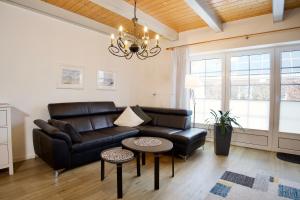 a living room with a black leather couch and a table at Hus Utspann in Nordstrand +46 photos