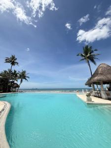a large swimming pool next to a beach with palm trees at Playa Tropical Resort Hotel in Currimao +6 photos