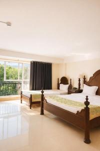 two beds in a large room with a window at Hoàng Lê Hotel in Ho Chi Minh City