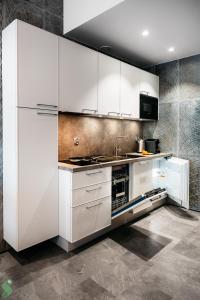 a kitchen with white cabinets and a stove at HANZA Pionier 2 pokoje i balkon SPA & Pool Parking by stayly in Szczecin