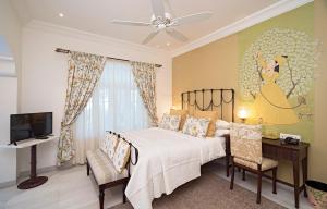 a bedroom with a bed and a desk and a television at The Rohet House in Jodhpur