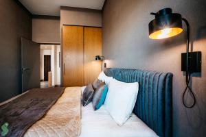 a bedroom with a bed with pillows and a lamp at HANZA Pionier 2 pokoje i balkon SPA & Pool Parking by stayly in Szczecin +18 photos