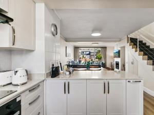 a kitchen with white cabinets and a living room at KnysnaQuays 4 in Knysna