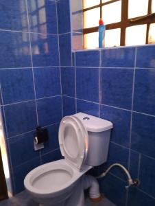 a blue tiled bathroom with a toilet and a window at SQ Acacia in Langata Rongai