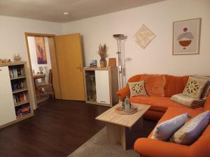 a living room with an orange couch and a table at Lütt Verbliev in Malchow