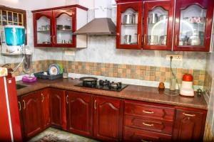 a kitchen with red wooden cabinets and a stove at Radiance Crystal in Pondicherry