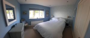 a bedroom with a white bed and two windows at River View - Stunning estuary views in Aldeburgh