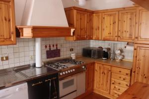 a kitchen with wooden cabinets and a stove top oven at Al Roser in Forno di Zoldo
