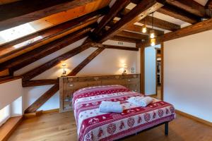 ein Schlafzimmer mit einem Bett in einem Zimmer mit Holzdecke in der Unterkunft Corleta 2 in Ovaro