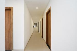 an empty corridor with white walls and wooden doors at Hotel O Noida Sky Suites Sector 44 Near botanical metro in Badarpur