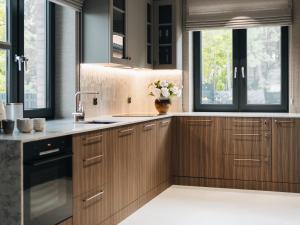 a kitchen with wooden cabinets and a sink and windows at Villa D'Jora in Mikołajki