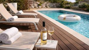 a bottle of wine and a glass next to a swimming pool at Cabril's Hills - Stunning Villa with Pool & Sea Views in Cabrils
