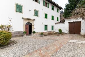an exterior view of a white building with green shutters at La Cort di Vigje 2 in Ovaro