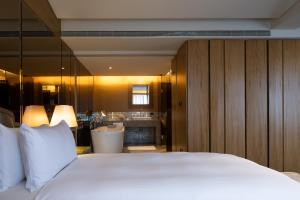 a bedroom with a large white bed and a bathroom at The Landis Taipei in Taipei
