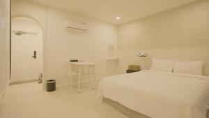 a white bedroom with a bed and a table at Jeju Stay Hotel in Jeju