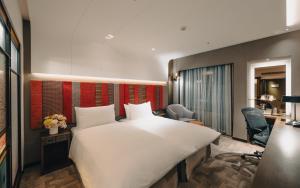 a hotel room with a large bed and a desk at The Landis Taipei in Taipei