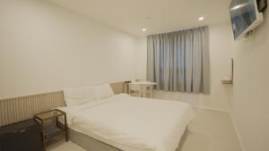 a bedroom with a white bed and a window at Jeju Stay Hotel in Jeju