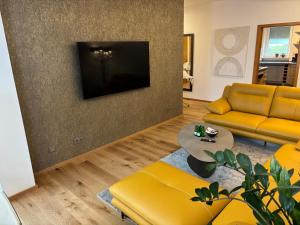 a living room with yellow furniture and a flat screen tv at Residence Loft in Friedrichshafen