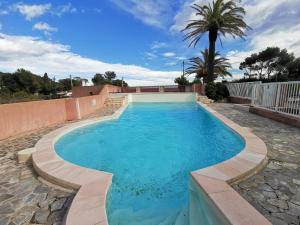 a swimming pool with blue water and a palm tree at Studio Serenity - Clim - WIFI - Parking - Piscine - Front de mer - Proche commerces et centre ville in Fréjus