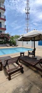 two picnic tables and an umbrella next to a swimming pool at Shanzu Beach Homes 105 in Mombasa