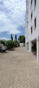 a large white building with a brick road next to it at Shanzu Beach Homes 105 in Mombasa
