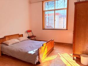 a bedroom with a bed and a window and a chair at Kulikuli Boy's Inn in Lijiang