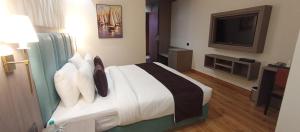 a hotel room with a bed and a flat screen tv at AairHotel in Karnal