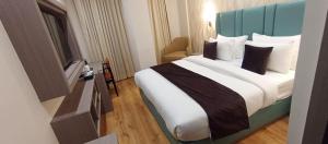 a bedroom with a large bed with a blue headboard at AairHotel in Karnal +5 photos