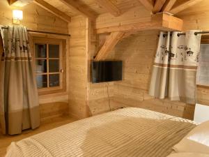a bedroom in a log cabin with a bed and a tv at Vertigo in Puy-Saint-Pierre