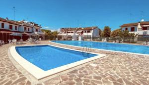 a swimming pool with blue water in a resort at GuestHost - Parco del Sole Residence Flat with Terrace in lido degli scacchi