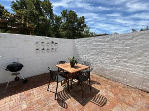 a table and chairs on a brick patio with a grill at The Sultan Cottage in Stellenbosch