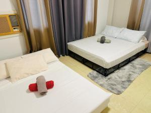 two beds in a hotel room with remotes on them at Oslob Cozy Home in Oslob