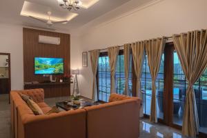 a living room with a couch and a television at Tranquil Resort - Blusalzz Collection, Wayanad - Kerala in Ambalavayal