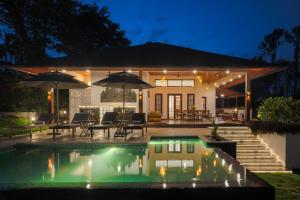 a house with a swimming pool at night at Tranquil Resort - Blusalzz Collection, Wayanad - Kerala in Ambalavayal
