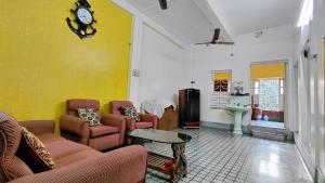 a living room with couches and a clock on the wall at Maya's Crest in Howrah