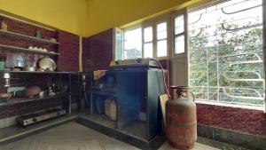 a kitchen with an old stove and a window at Maya's Crest in Howrah