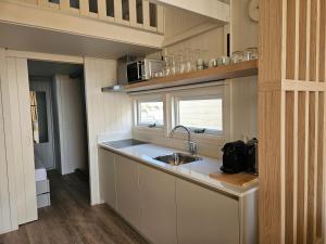 a small kitchen with a sink and a window at Skip Inn Strandhuisjes in Katwijk aan Zee
