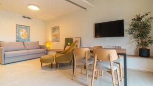 a living room with a couch and a table and chairs at Ohtels Les Oliveres in Perelló