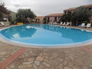 a large blue swimming pool with chairs around it at Badesi Apartment - Mirto in Badesi