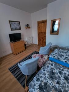 a bedroom with a bed and two chairs and a television at Penzión Evka in Poprad