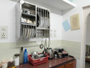 a kitchen with a counter with dishes in a cabinet at Alice's Cozy Abode in Udupi
