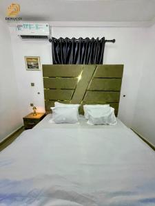 a bedroom with a large white bed with two pillows at Derucci Luxury Apartment in Owerri