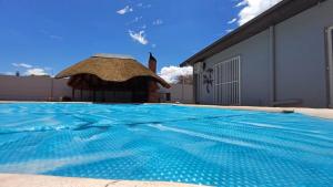 a swimming pool with a gazebo next to a building at Pangolin self-catering accommodation in Windhoek