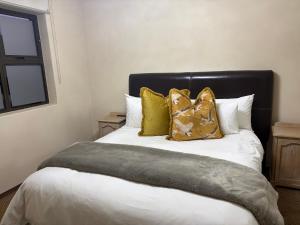 a bedroom with a bed with gold pillows on it at Swanepoel Guesthouse in Jeffreys Bay