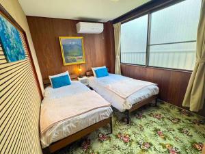 a small room with two beds and a window at 媛楽園Himerakuen in Matsuyama