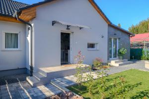 a white house with a staircase leading to the front door at Majoros Garden Apartman in Siófok
